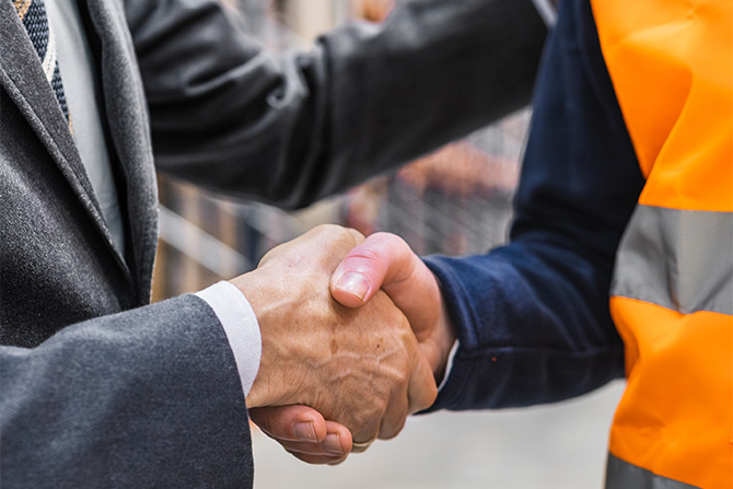 Man in suit shaking hands with man in orange work vest